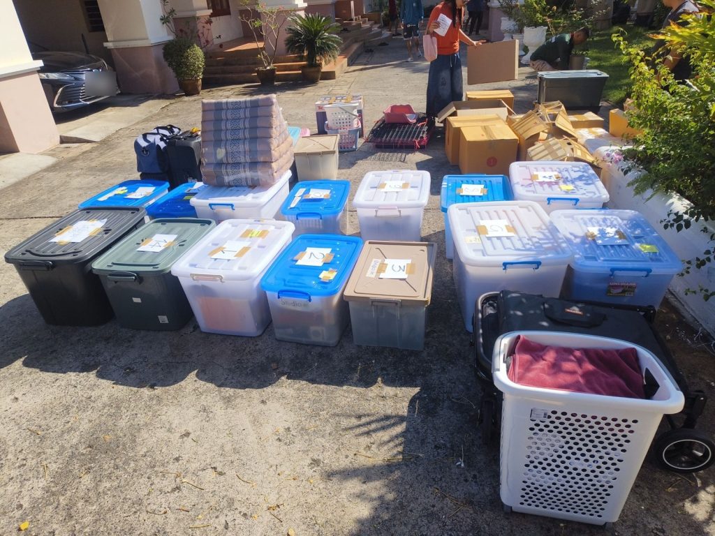 กล่องพลาสติกติดเลขกำกับตั้งเรียงหน้าบ้าน เตรียมขนขึ้นรถ
